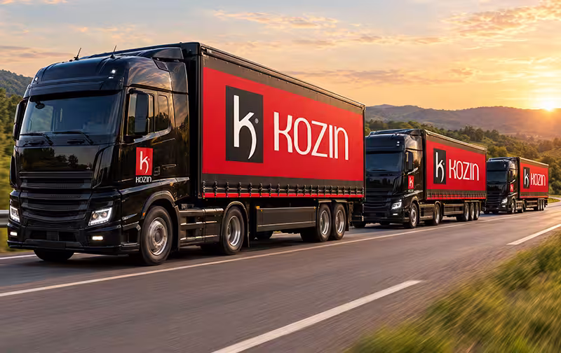Caminhões com a marca Kozin em comboio numa rodovia ao entardecer